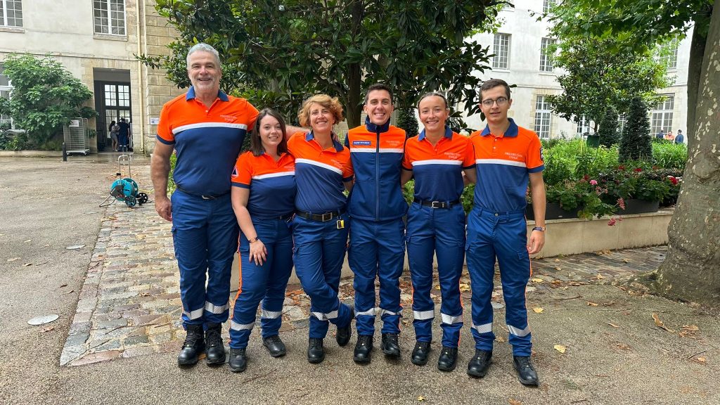 Six bénévoles de la Protection Civile en uniforme bleu et orange
