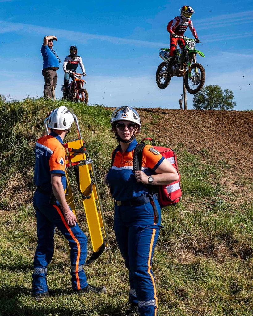 Deux bénévoles de la Protection Civile en uniforme bleu et orange sur un circuit de moto cross