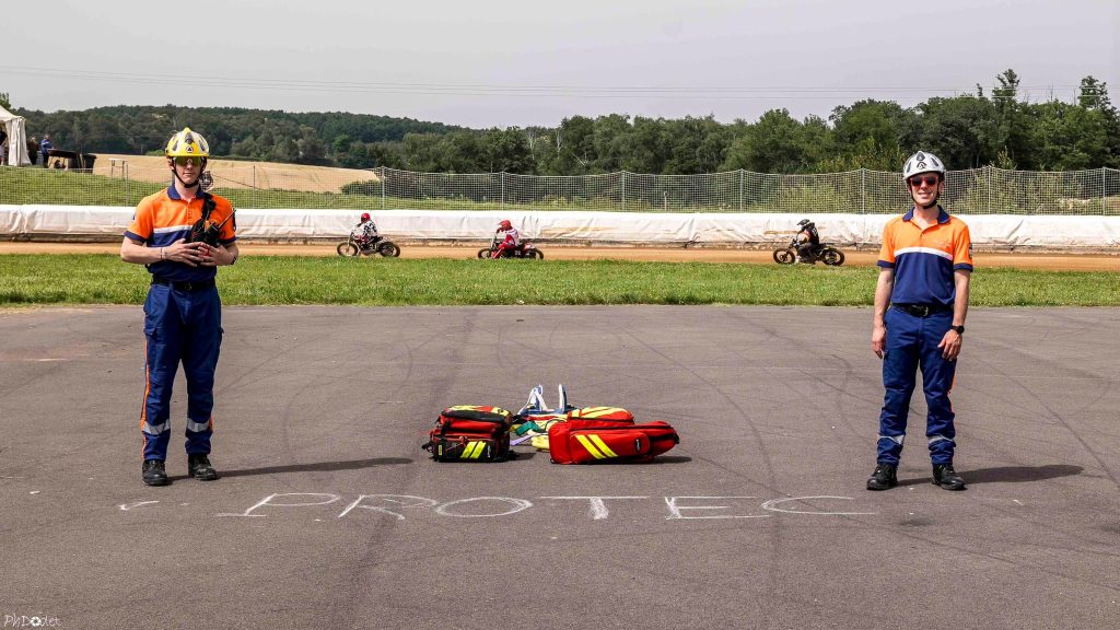 deux bénévoles de la protection civile sur un circuit, en uniforme bleu et orange