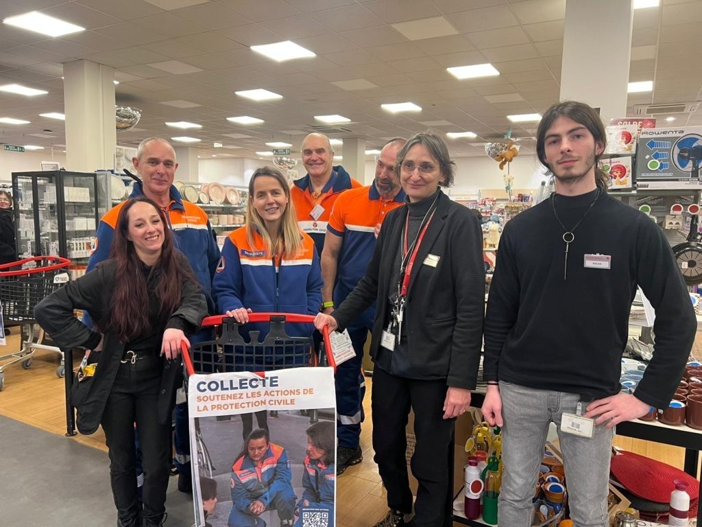 4 bénévoles de la Protection Civile en uniforme bleu et orange dans un magasin Monoprix